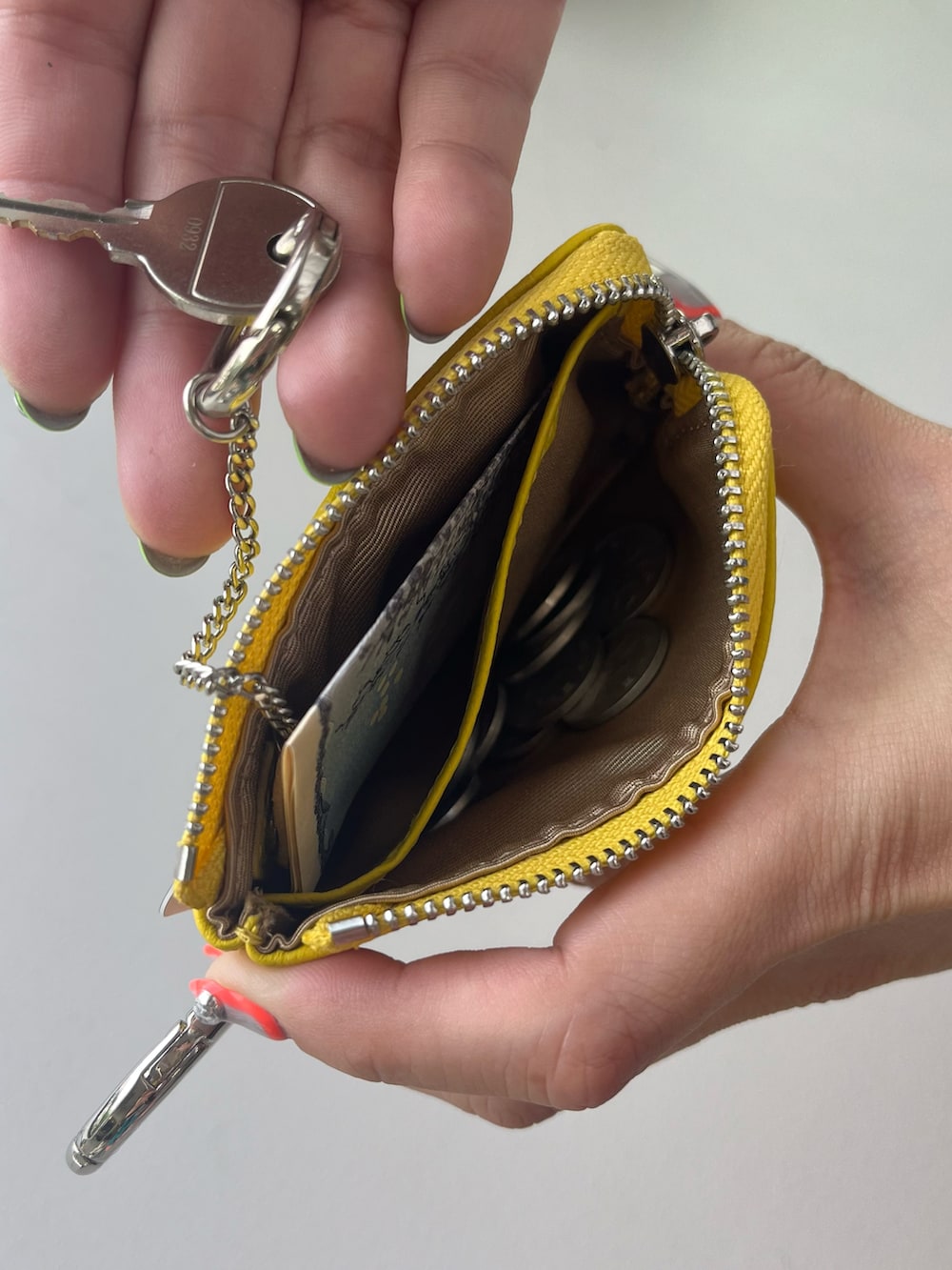 ホワイト系のポーチ、グリーン系の生活家電、イエロー系のパスケースを着用したレディースの春コーディネートの5枚目の写真