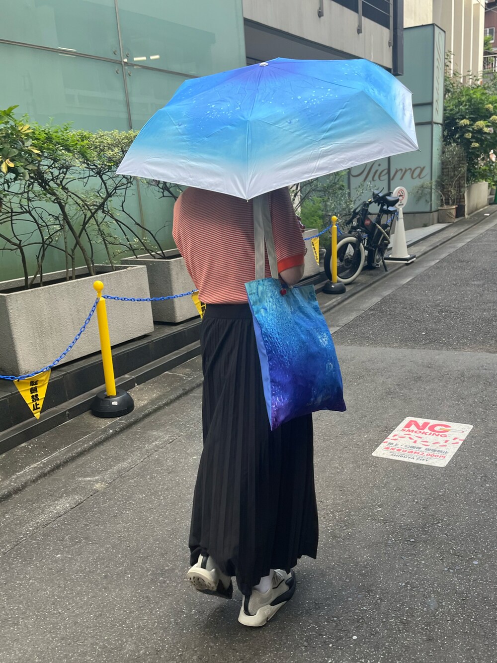 ブルー系のトートバッグ、ホワイト系のスニーカー、ブルー系の折りたたみ傘を着用したレディースの夏コーディネートの2枚目の写真