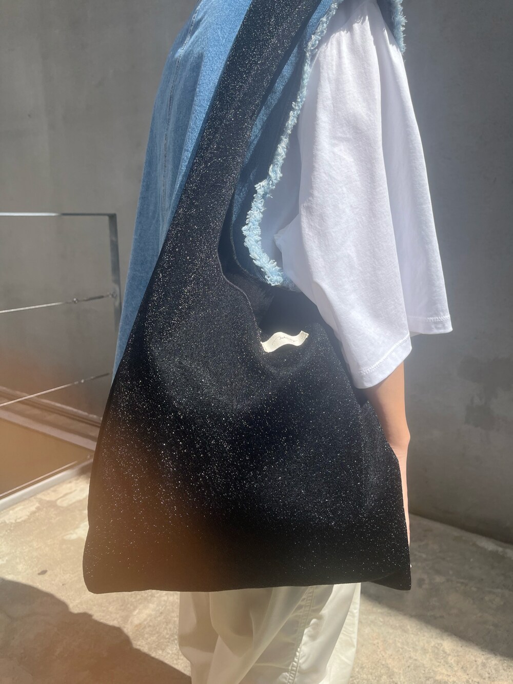 ブルー系のベスト、ホワイト系のその他パンツ、ブラック系のトートバッグを着用したレディースの秋コーディネートの2枚目の写真