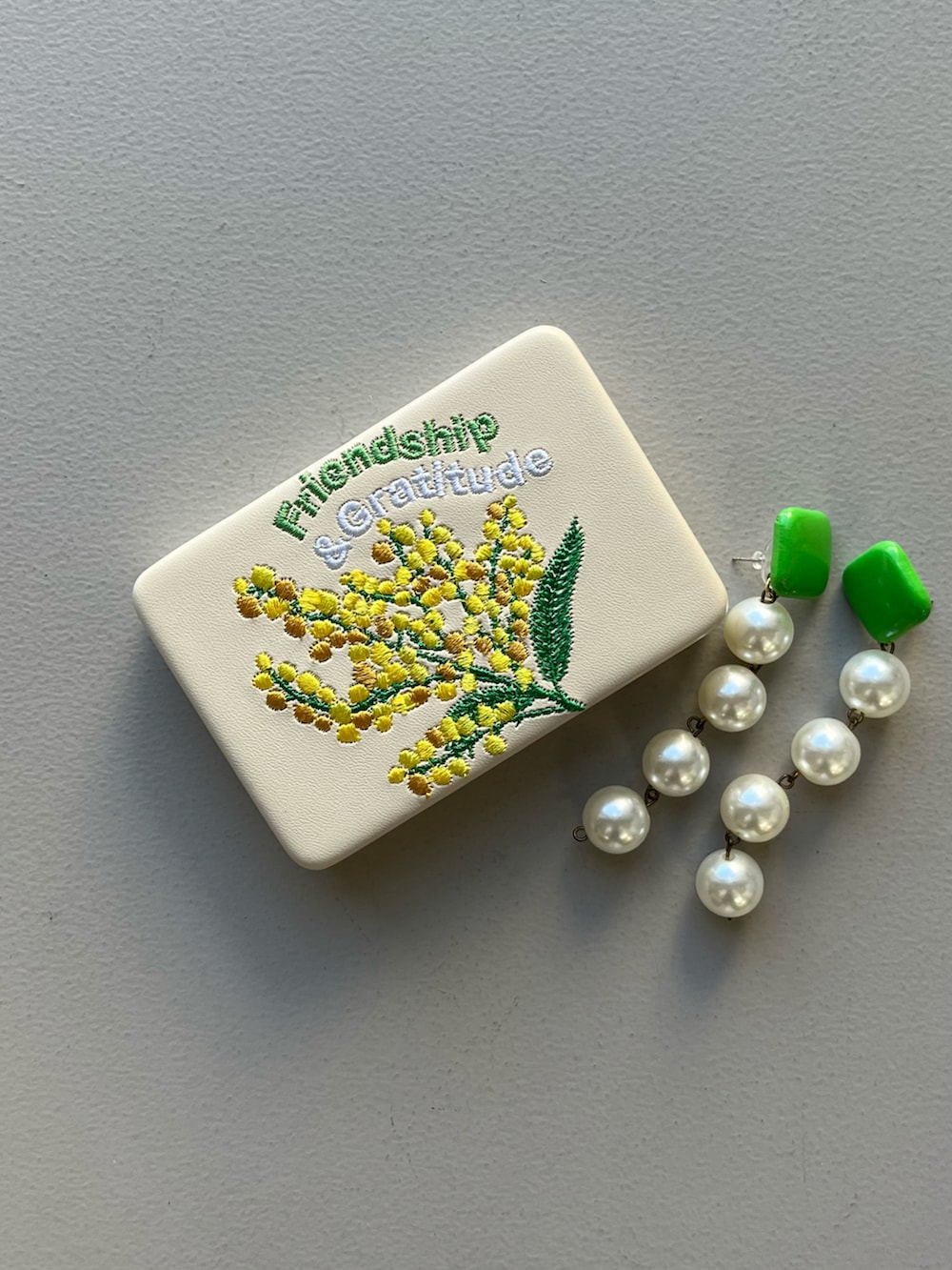 イエロー系のポーチ、シルバー系の財布、ピンク系のポーチを着用したレディースの春コーディネートの3枚目の写真