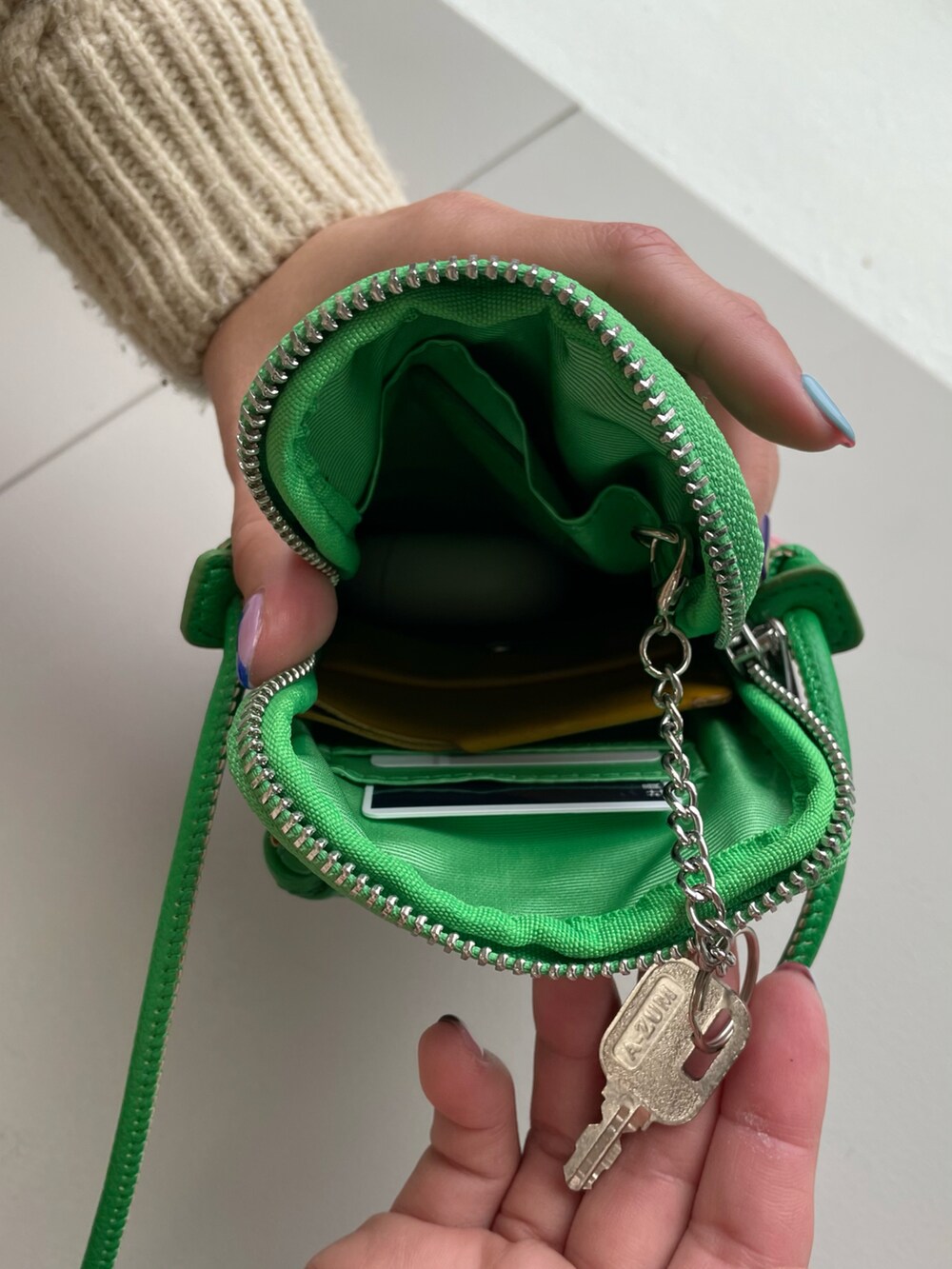 グリーン系のショルダーバッグ、ホワイト系のスニーカー、ベージュ系のニット/セーターを着用したレディースの冬コーディネートの5枚目の写真