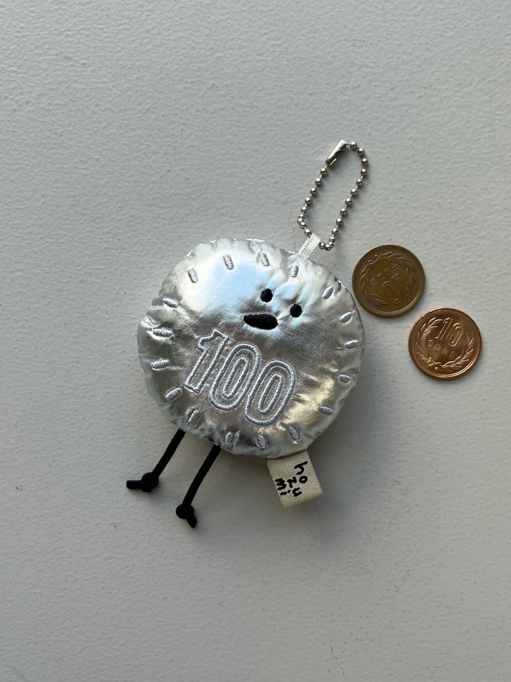 シルバー系のチャーム、ベージュ系の財布、グリーン系のポーチを着用したレディースの秋コーディネートの3枚目の写真