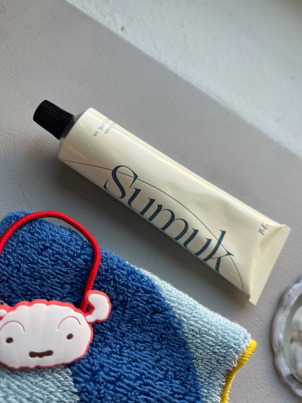 オレンジ系の財布、ブルー系のキーホルダー、ブルー系のハンカチ/ハンドタオルを着用したレディースの春コーディネートの3枚目の写真