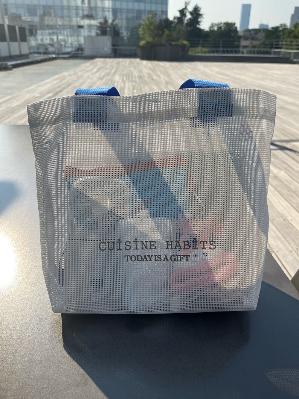 ホワイト系のトートバッグ、ブルー系のポーチ、シルバー系の財布を着用したレディースの夏コーディネートの3枚目の写真