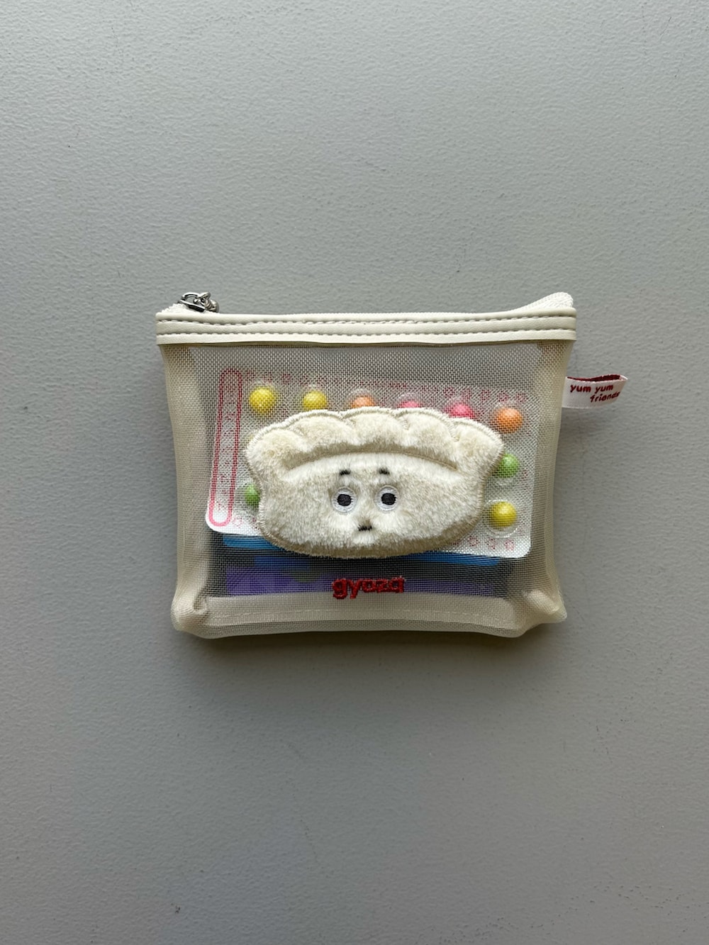 オレンジ系のポーチ、ホワイト系のチャーム、グレー系のポーチを着用したレディースの春コーディネートの5枚目の写真