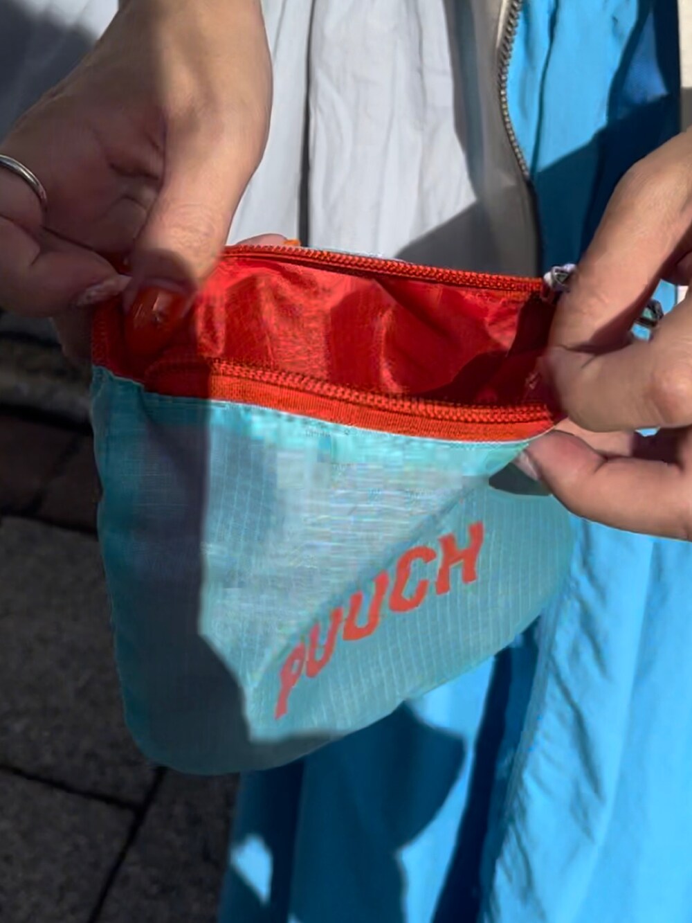 ブルー系のショルダーバッグ、ホワイト系のベスト、ブルー系のスカートを着用したレディースの夏コーディネートの3枚目の写真