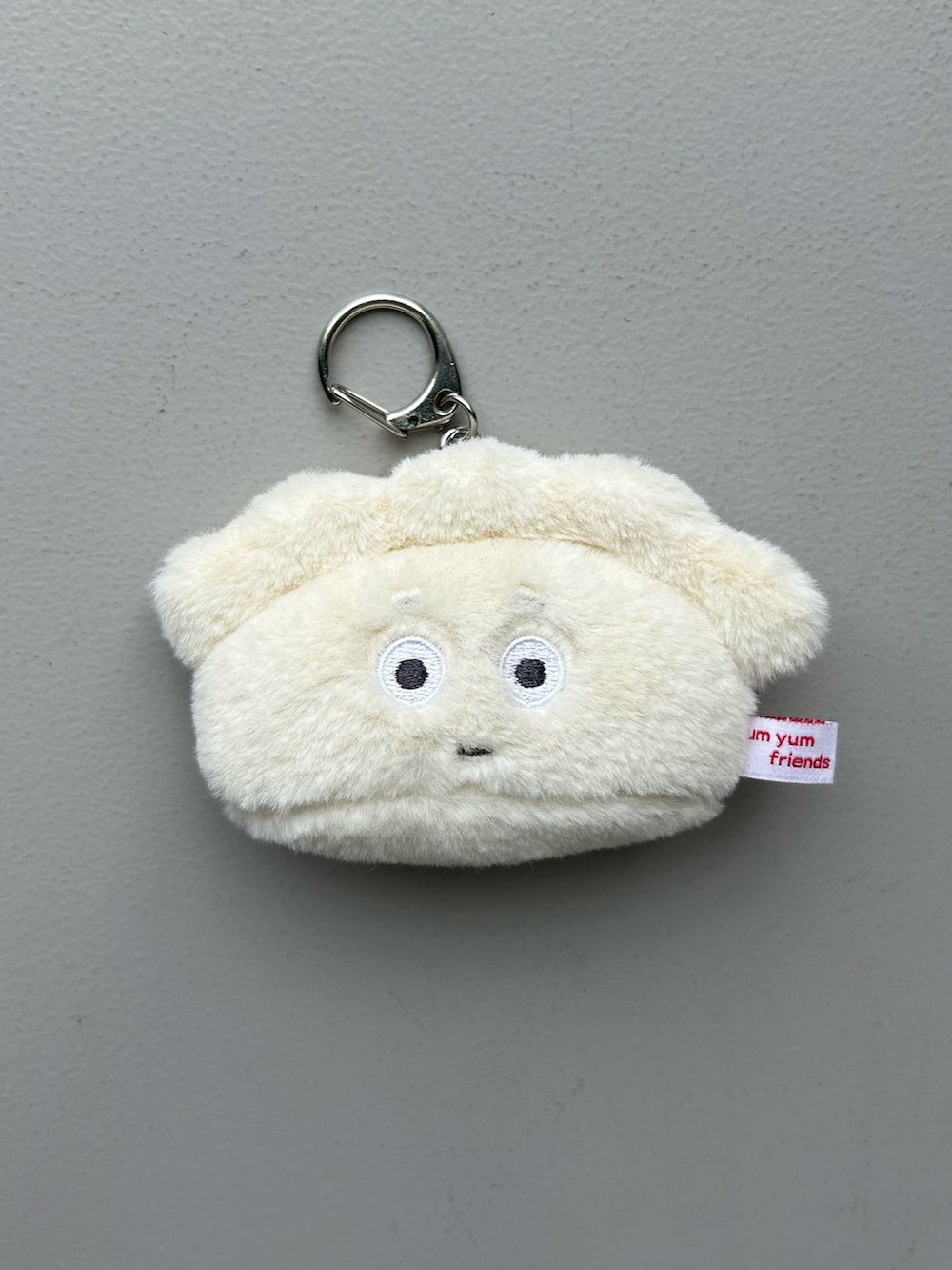 グリーン系の財布、グレー系のポーチ、ホワイト系のチャームを着用したレディースの春コーディネートの3枚目の写真