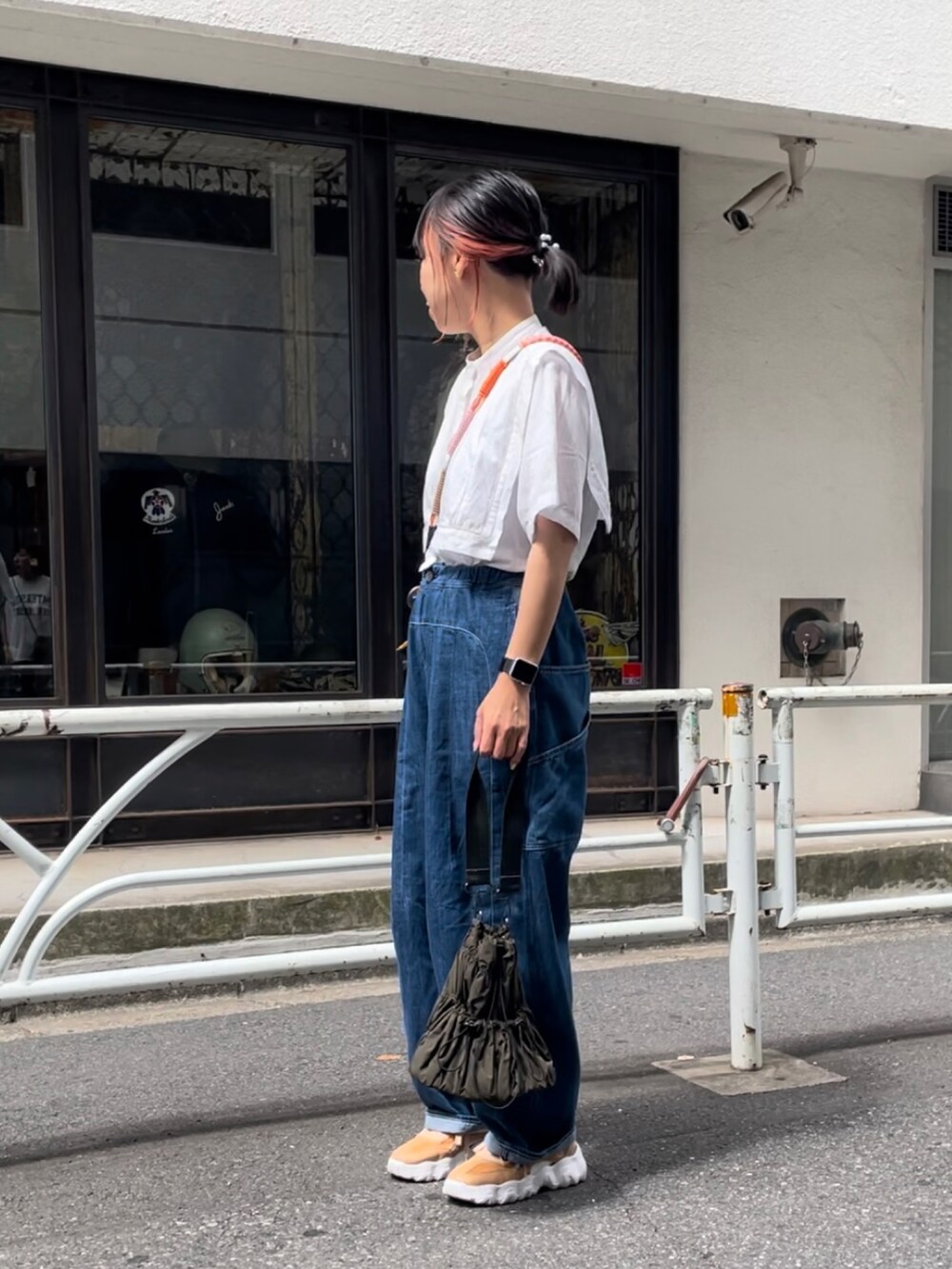 グリーン系のトートバッグ、ベージュ系のスニーカー、ブルー系のパンツを着用したレディースの夏コーディネートの2枚目の写真