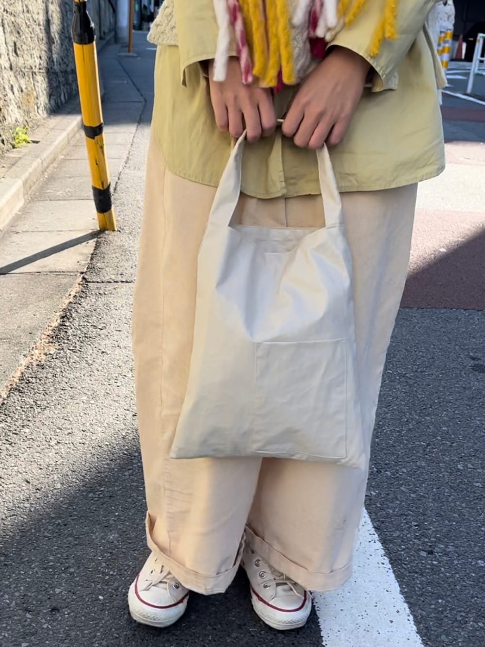 ホワイト系のトートバッグ、ホワイト系のベスト、ホワイト系のスニーカーを着用したレディースの秋コーディネートの2枚目の写真