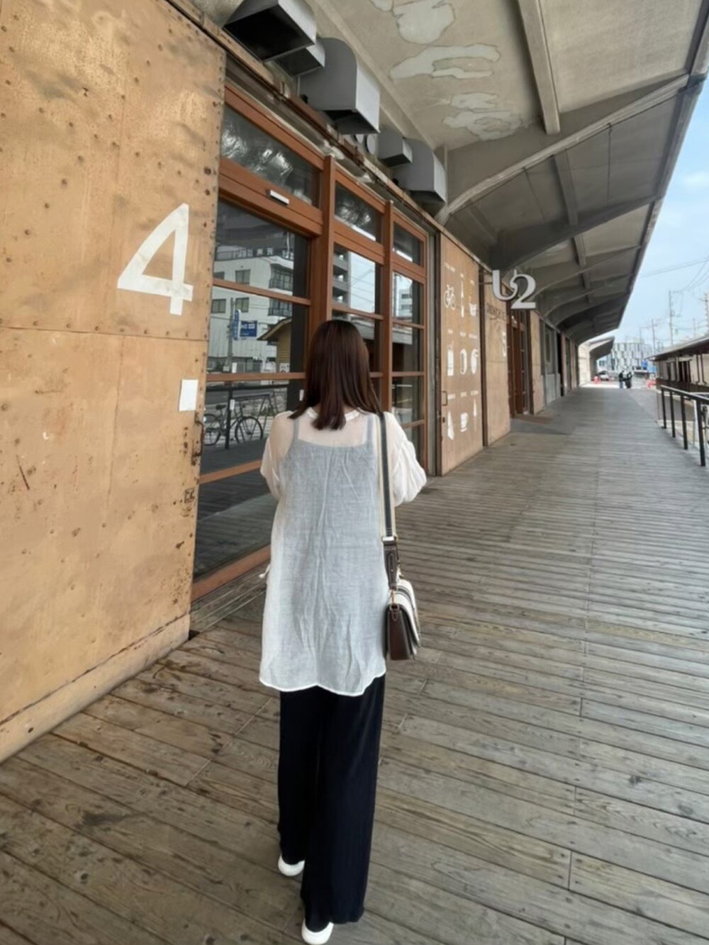 ホワイト系のシャツ/ブラウス、ブラック系のスラックス、ブラウン系のハンドバッグを着用したレディースの春コーディネートの2枚目の写真