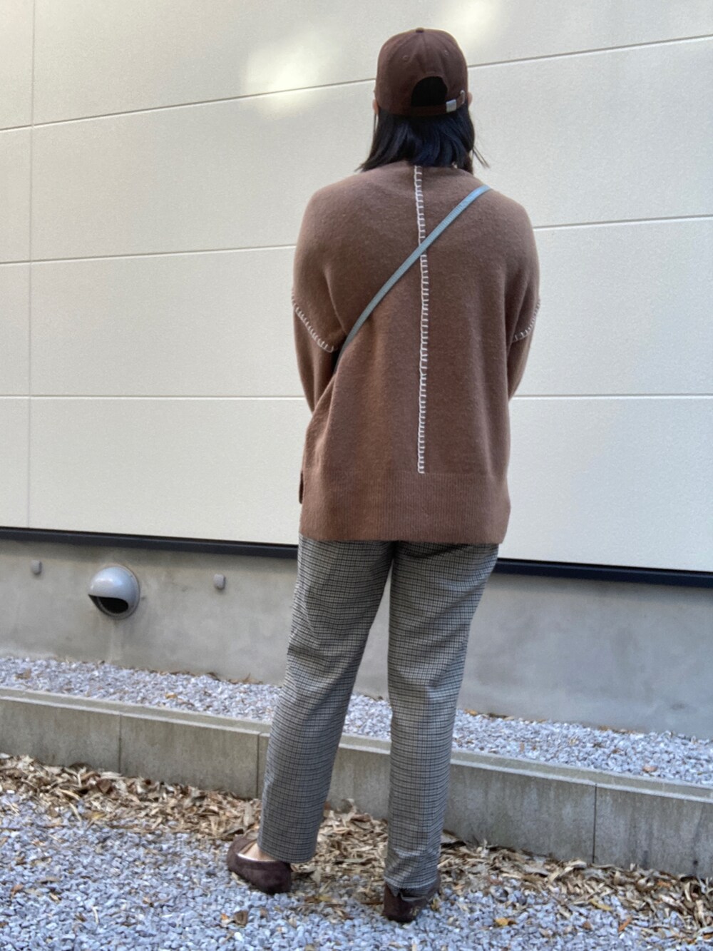 ブルー系のショルダーバッグ、ブラウン系のパンツ、ブラウン系のローファーを着用したレディースの秋コーディネートの2枚目の写真