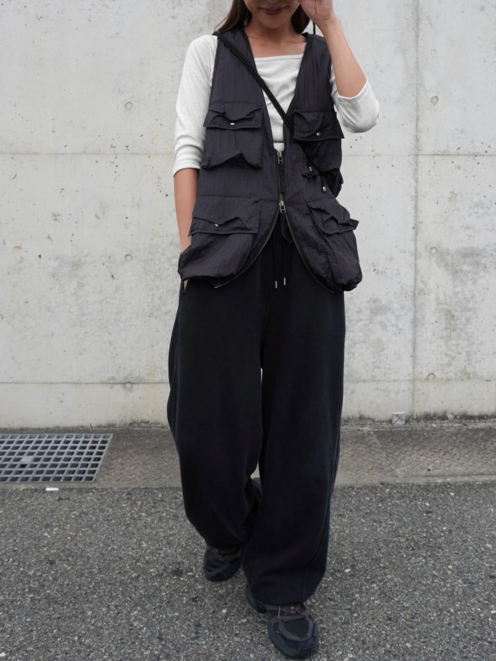 ブラック系のスウェットパンツ、ブラック系のベスト、グレー系のトップスを着用したレディースの秋コーディネートの3枚目の写真