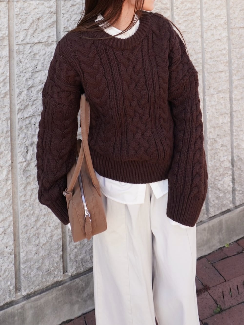 ブラウン系のニット/セーター、ホワイト系のパンツ、ベージュ系のショルダーバッグを着用したレディースの冬コーディネートの2枚目の写真