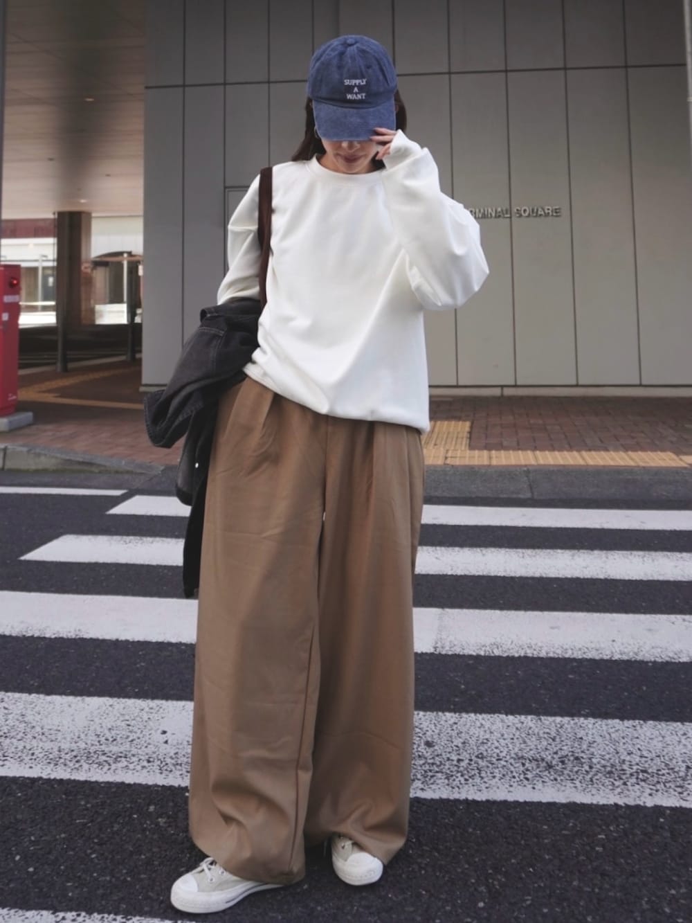 ホワイト系のスウェット、ベージュ系のスラックス、ブルー系のキャップを着用したレディースの冬コーディネートの3枚目の写真