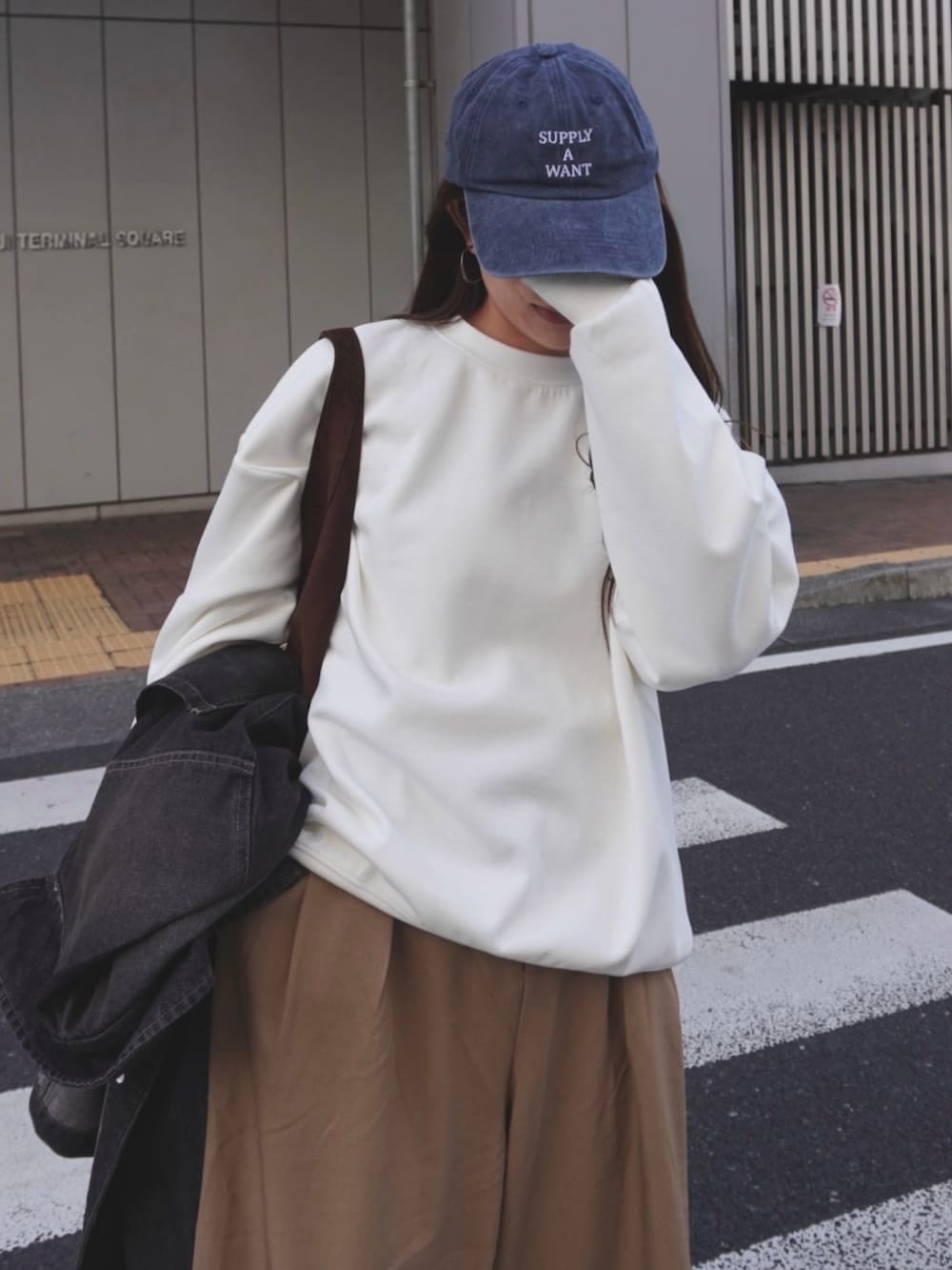 ホワイト系のスウェット、ベージュ系のスラックス、ブルー系のキャップを着用したレディースの冬コーディネートの4枚目の写真