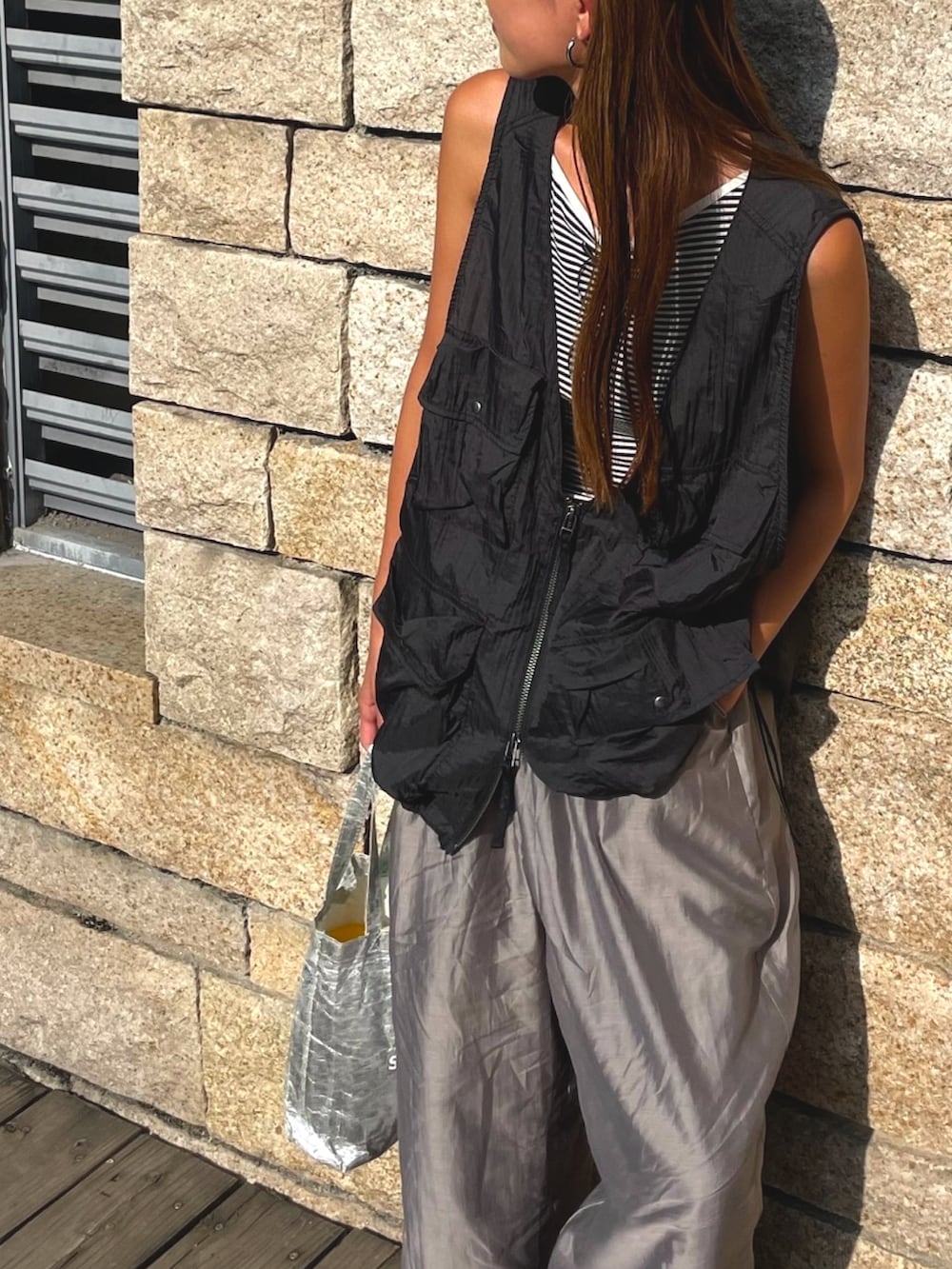 ブラック系のベスト、グレー系のパンツ、ブラック系のスリッポンを着用したレディースの秋コーディネートの5枚目の写真