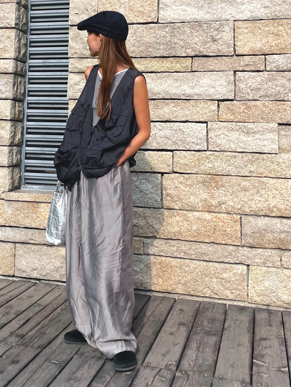 ブラック系のベスト、グレー系のパンツ、ブラック系のスリッポンを着用したレディースの秋コーディネートの2枚目の写真