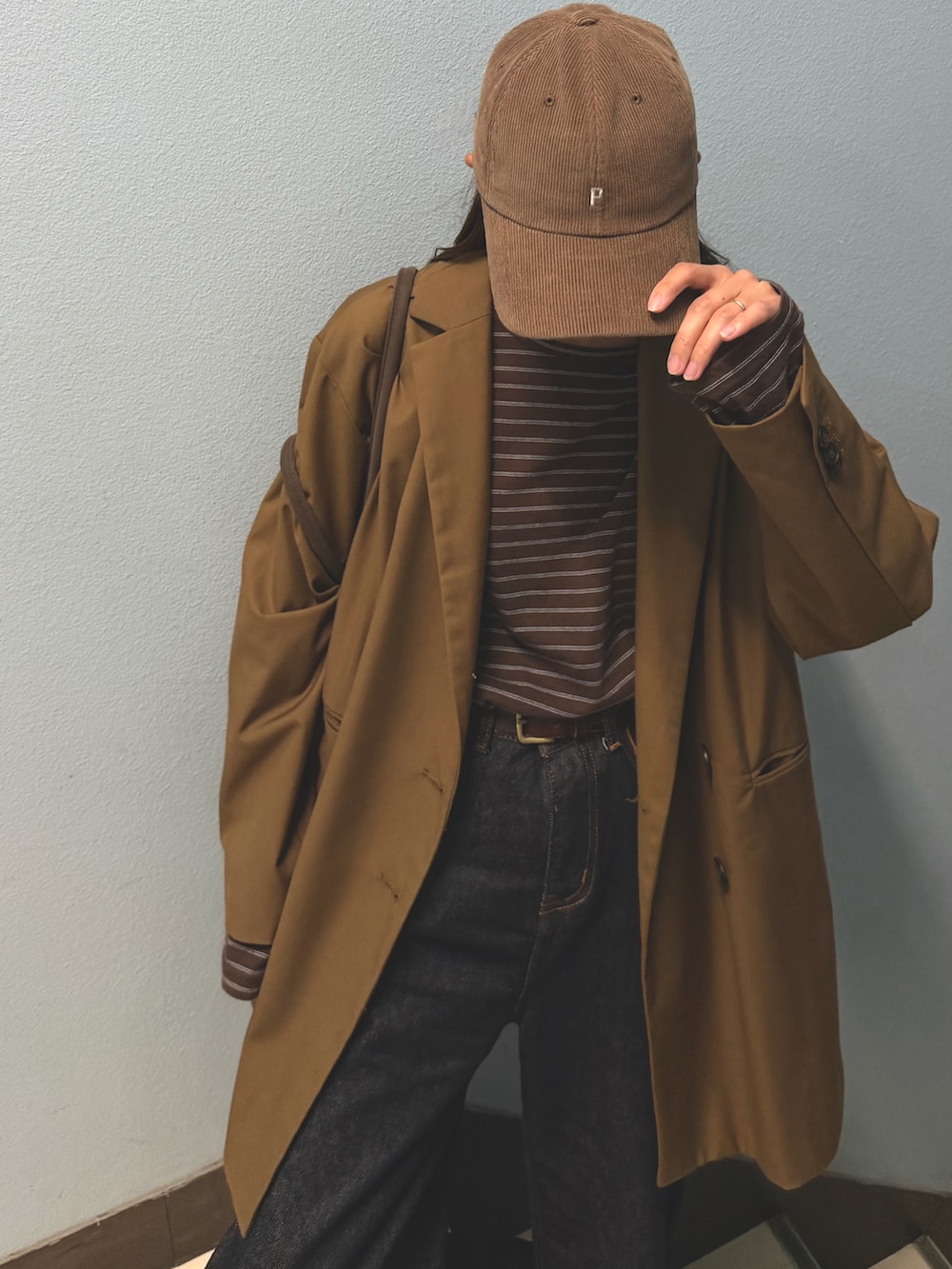 ブラウン系のテーラードジャケット、ブルー系のデニムパンツ、ブラウン系のスニーカーを着用したレディースの秋コーディネートの4枚目の写真