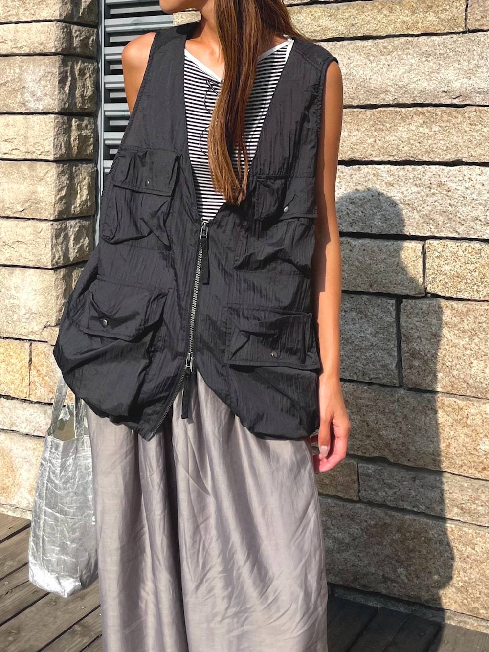 ブラック系のベスト、グレー系のパンツ、ブラック系のスリッポンを着用したレディースの秋コーディネートの4枚目の写真