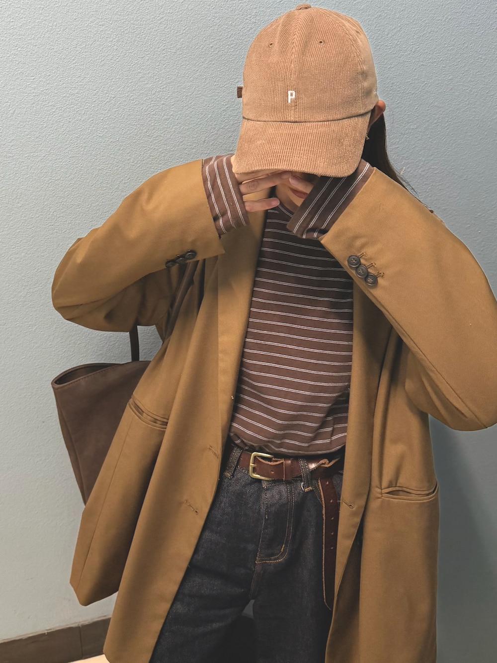 ブラウン系のテーラードジャケット、ブルー系のデニムパンツ、ブラウン系のスニーカーを着用したレディースの秋コーディネートの2枚目の写真