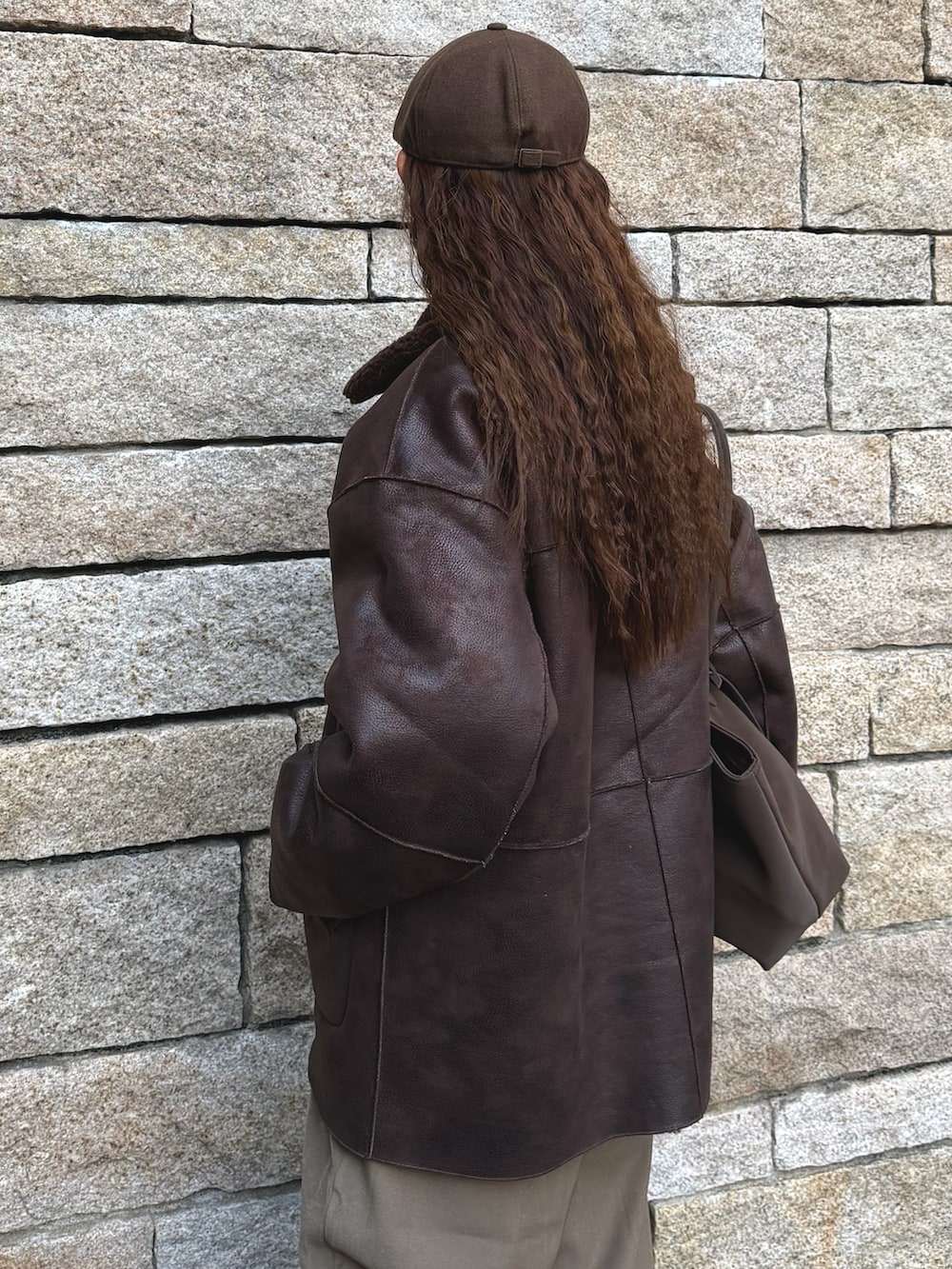 ブラウン系のムートンコート、ベージュ系のスラックス、ブラウン系のローファーを着用したレディースの冬コーディネートの5枚目の写真