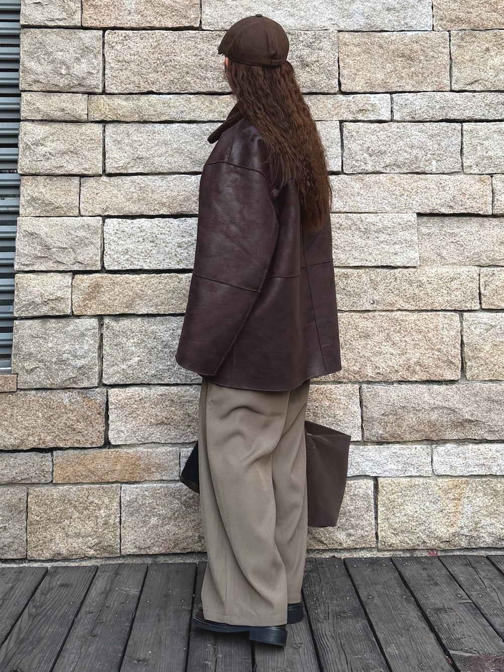 ブラウン系のムートンコート、ベージュ系のスラックス、ブラウン系のローファーを着用したレディースの冬コーディネートの2枚目の写真