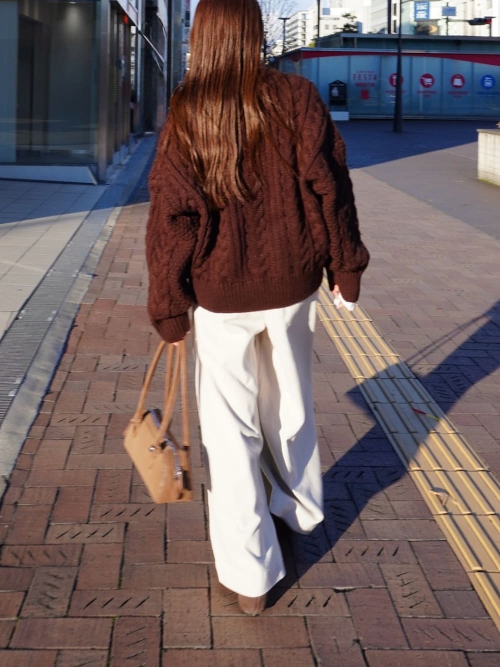 ブラウン系のニット/セーター、ホワイト系のパンツ、ベージュ系のショルダーバッグを着用したレディースの冬コーディネートの5枚目の写真