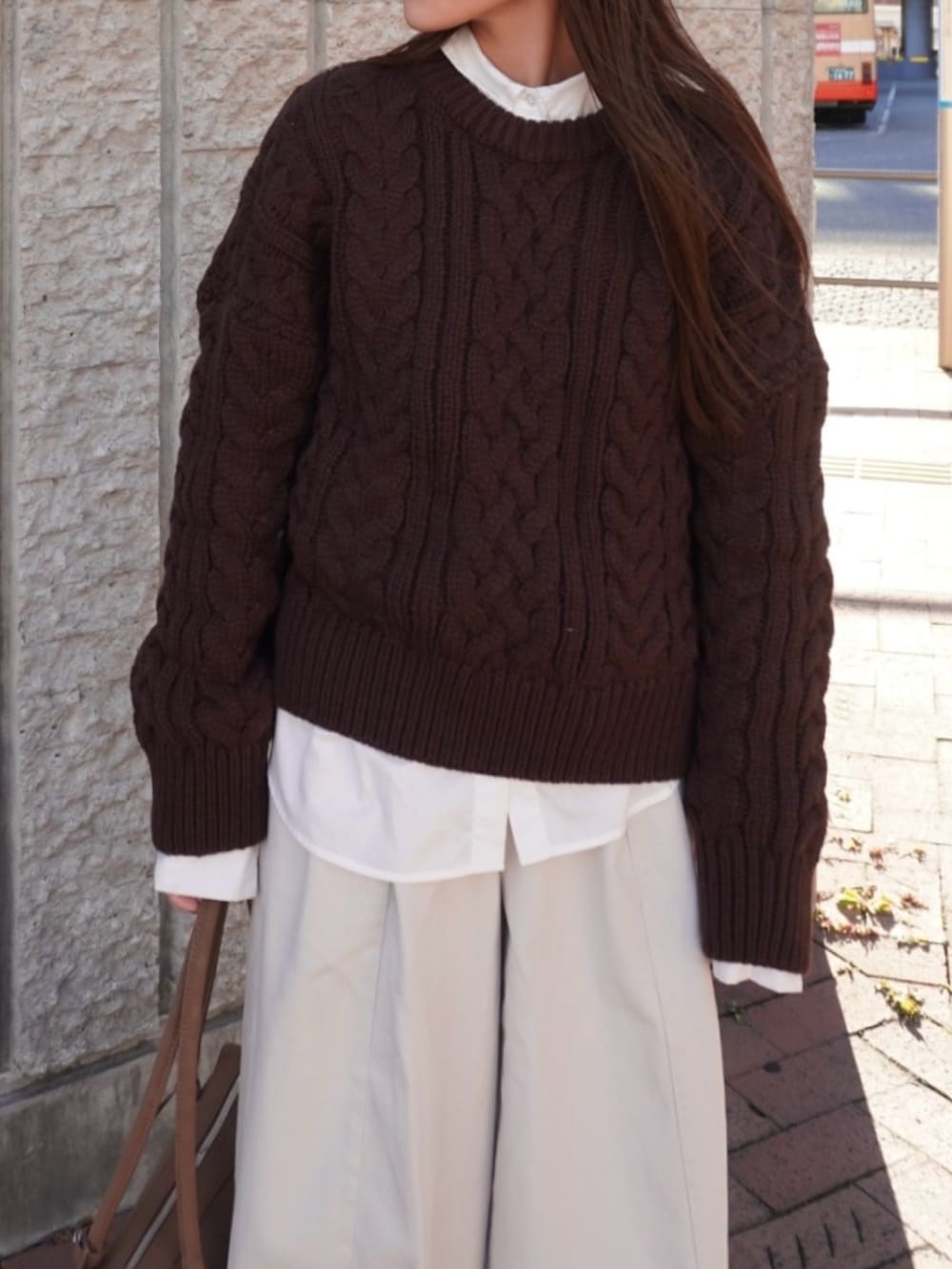 ブラウン系のニット/セーター、ホワイト系のパンツ、ベージュ系のショルダーバッグを着用したレディースの冬コーディネートの3枚目の写真