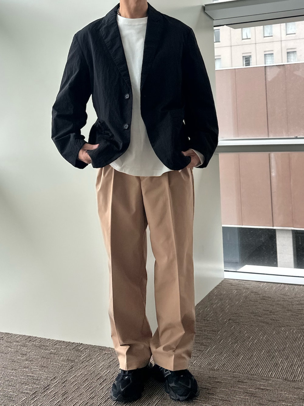 ブラック系のテーラードジャケット、ホワイト系のTシャツ/カットソー、ベージュ系のチノパンツを着用したメンズの秋コーディネートの2枚目の写真