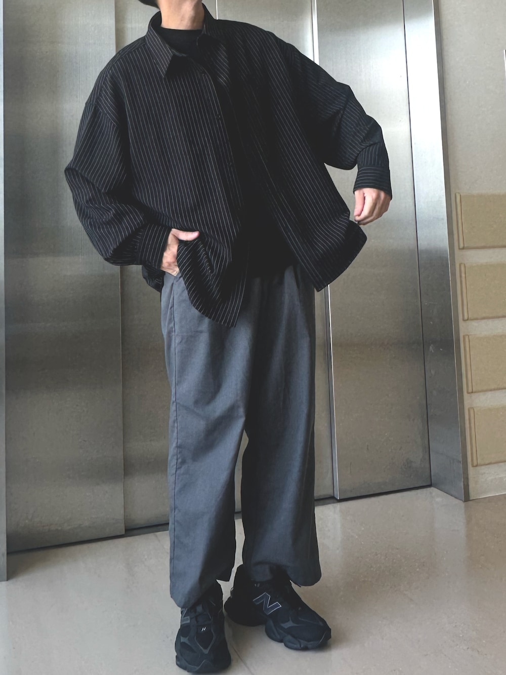 ブラック系のシャツ/ブラウス、グレー系のスラックス、ブラック系のスニーカーを着用したメンズの夏コーディネートの2枚目の写真