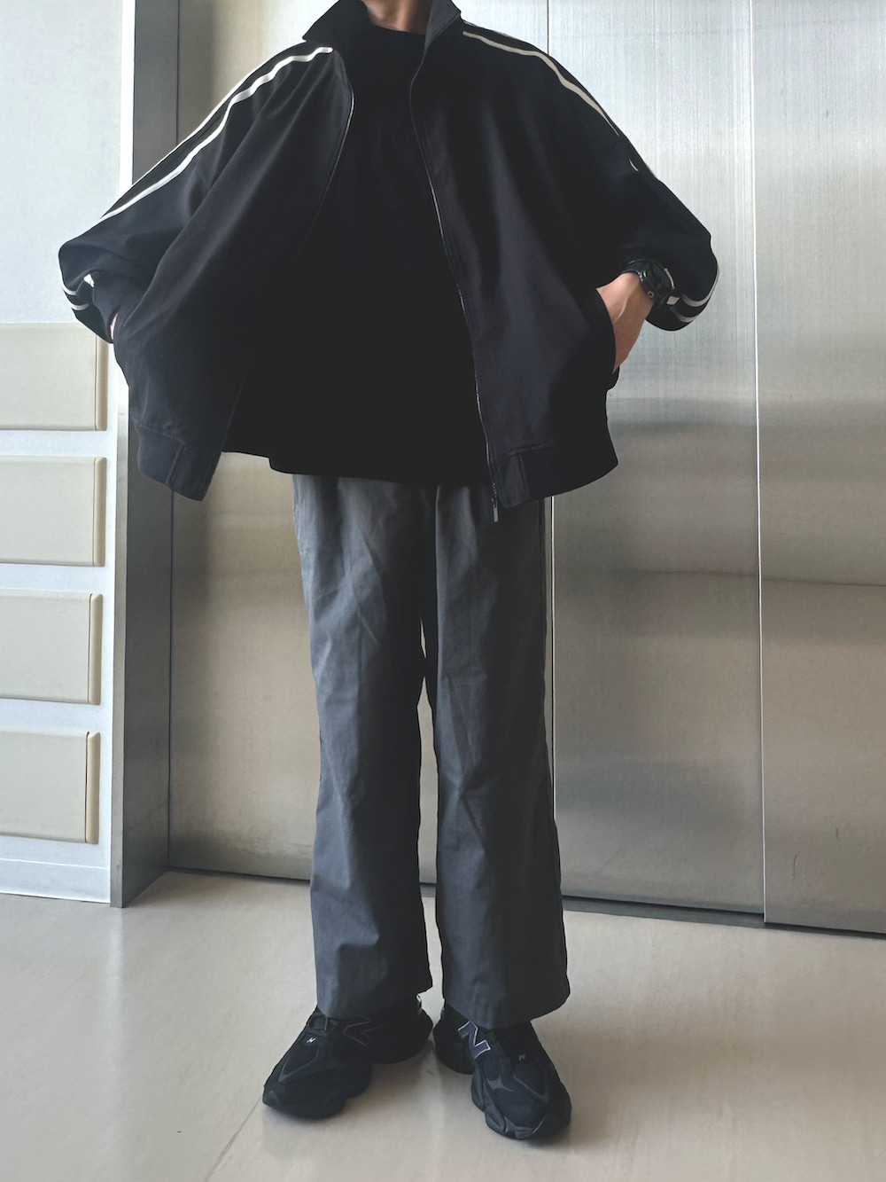 ブラック系のジャージ、グレー系のスラックス、ブラック系のスニーカーを着用したメンズの夏コーディネートの2枚目の写真