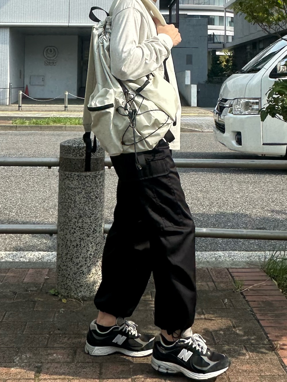 ベージュ系のTシャツ/カットソー、ホワイト系のバックパック/リュック、ブラック系のカーゴパンツを着用したメンズの夏コーディネートの2枚目の写真