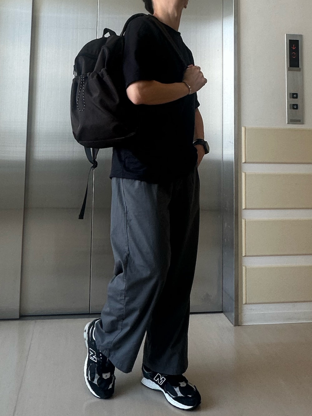 ブラウン系のバックパック/リュック、ブラック系のTシャツ/カットソー、シルバー系のブレスレットを着用したメンズの夏コーディネートの2枚目の写真