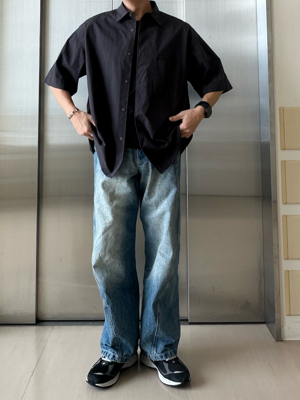 ブルー系のデニムパンツ、ブラック系のスニーカー、グレー系のシャツ/ブラウスを着用したメンズの秋コーディネートの2枚目の写真