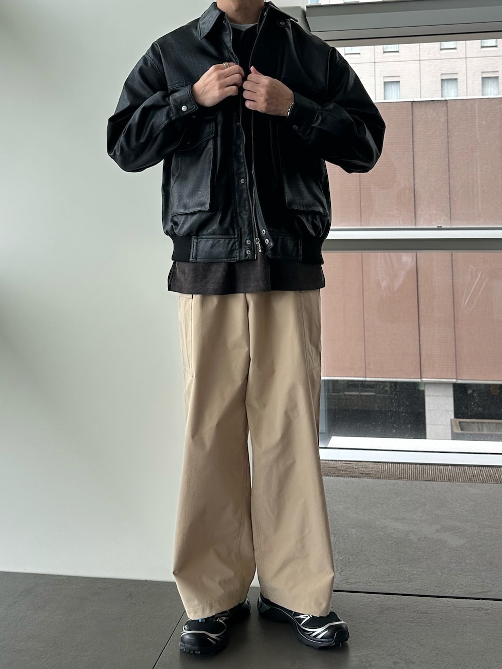 ブラック系のブルゾン、ブラウン系のTシャツ/カットソー、ベージュ系のカーゴパンツを着用したメンズの秋コーディネートの2枚目の写真