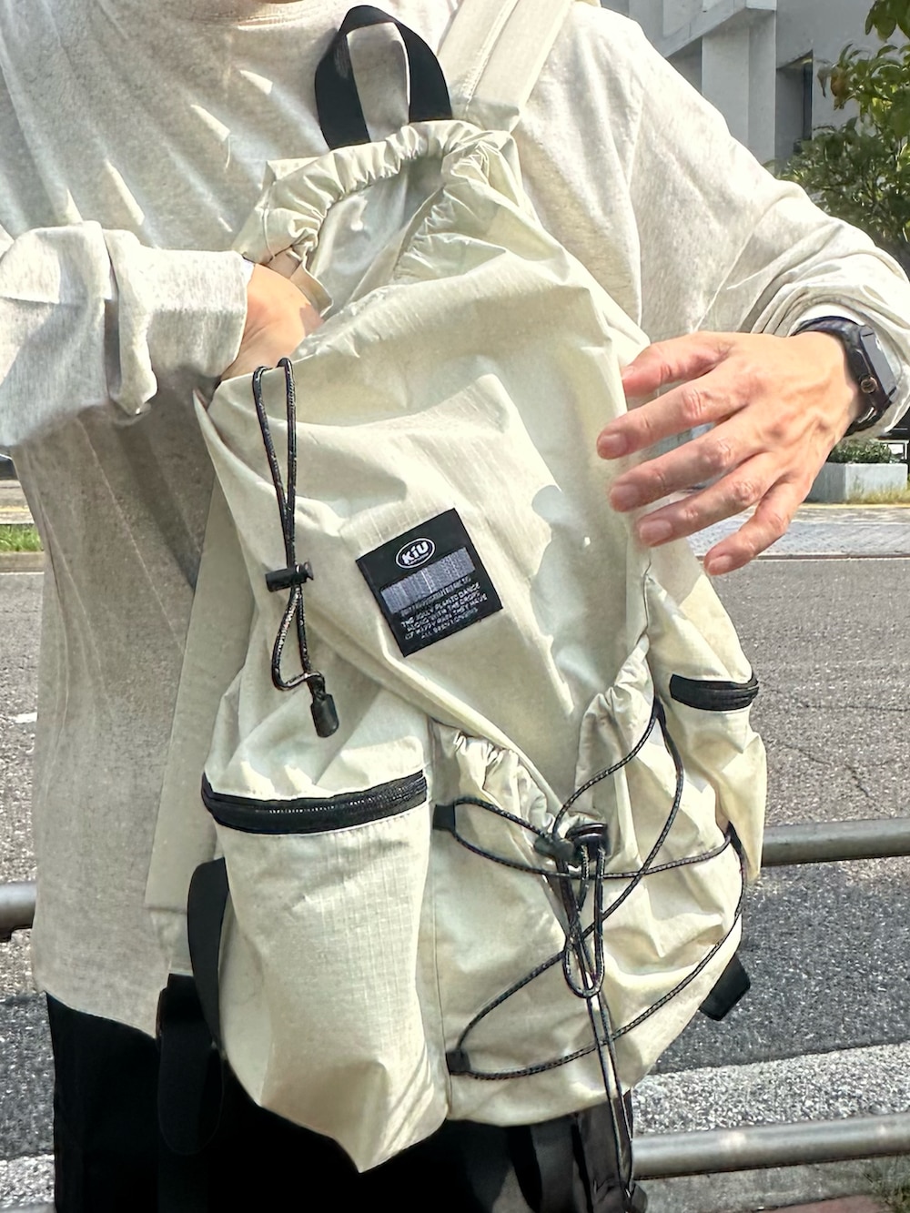 ベージュ系のTシャツ/カットソー、ホワイト系のバックパック/リュック、ブラック系のカーゴパンツを着用したメンズの夏コーディネートの5枚目の写真