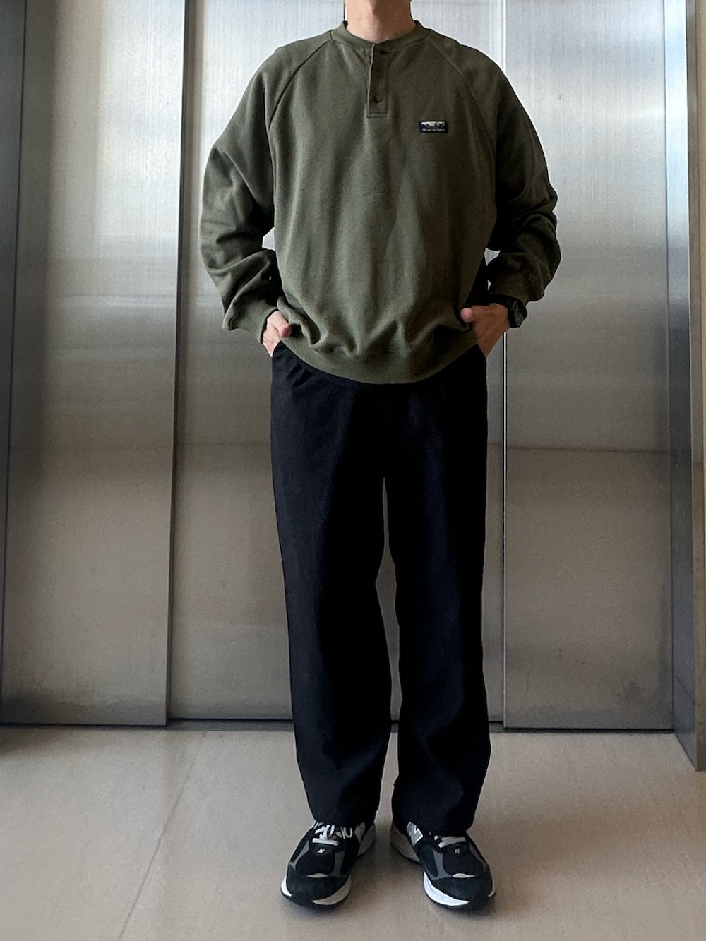グリーン系のスウェット、ブラック系のその他パンツ、ブラック系のスニーカーを着用したメンズの秋コーディネートの2枚目の写真