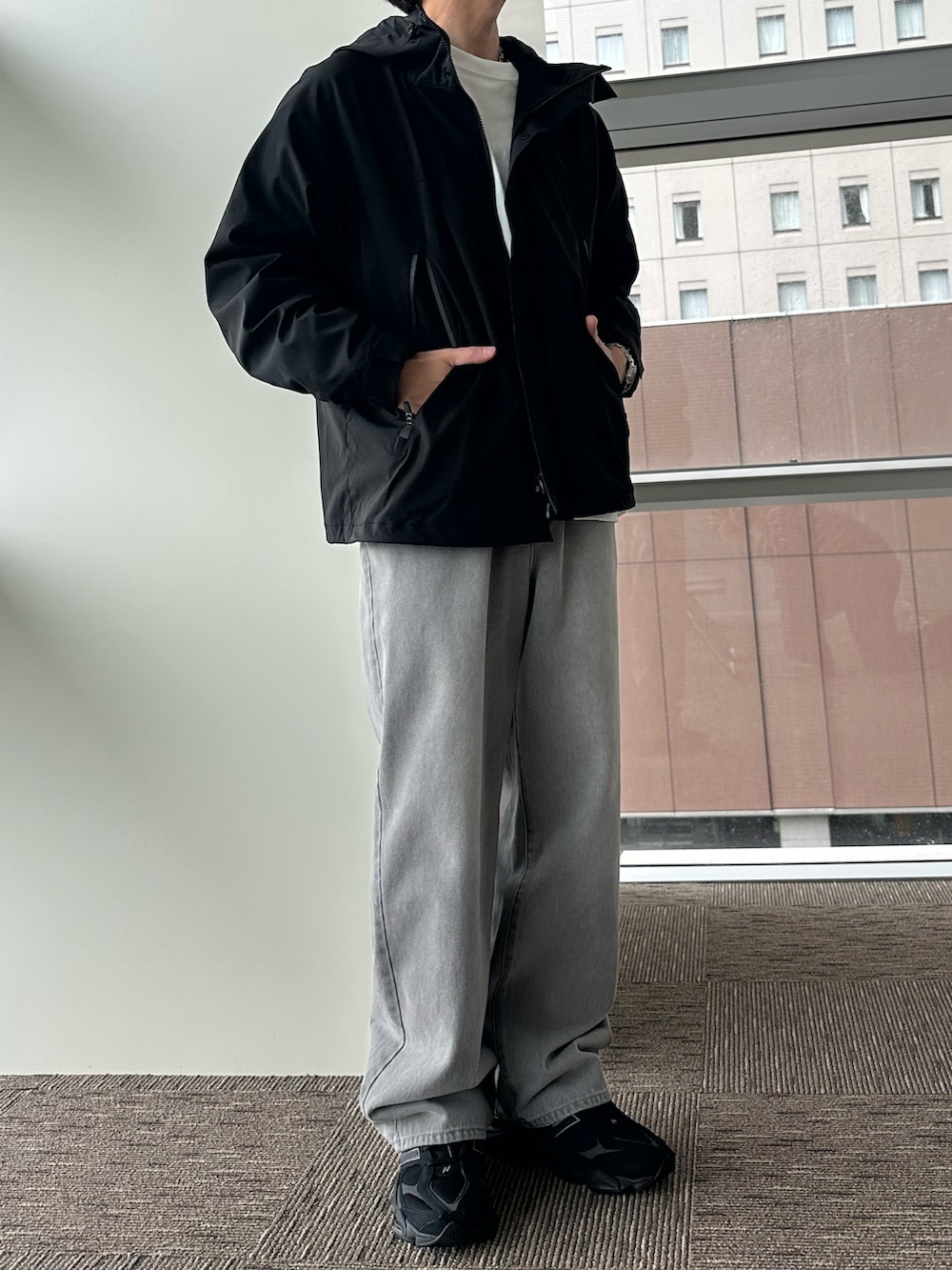 ブラック系のマウンテンパーカー、ホワイト系のTシャツ/カットソー、グレー系のデニムパンツを着用したメンズの秋コーディネートの2枚目の写真