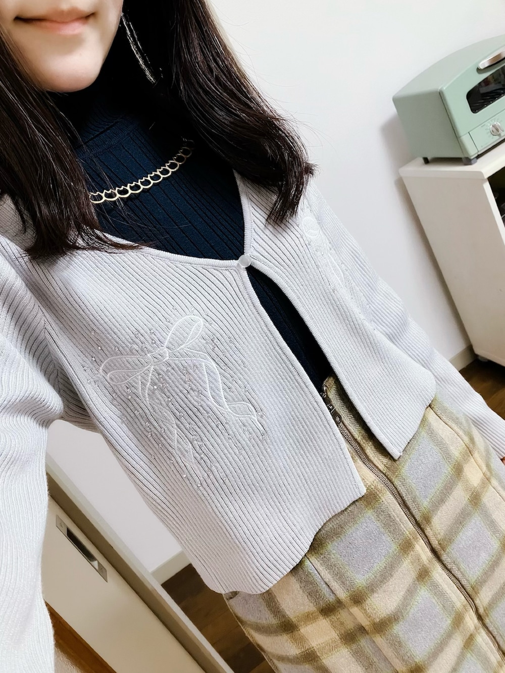 グレー系のカーディガン/ボレロ、グリーン系のスカート、ホワイト系のブーツを着用したレディースの秋コーディネートの2枚目の写真