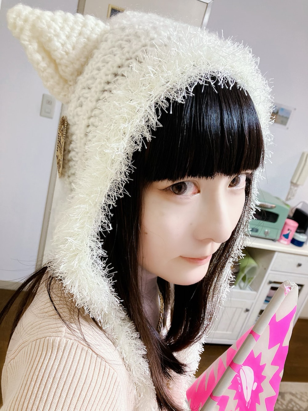 ピンク系のカーディガン/ボレロ、ベージュ系のスカート、ホワイト系のブーツを着用したレディースの秋コーディネートの2枚目の写真