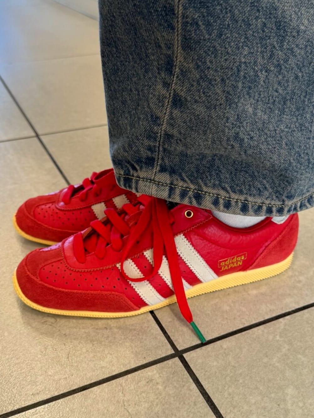 ブルー系のポロシャツ、レッド系のスニーカーを着用したレディースの夏コーディネートの2枚目の写真