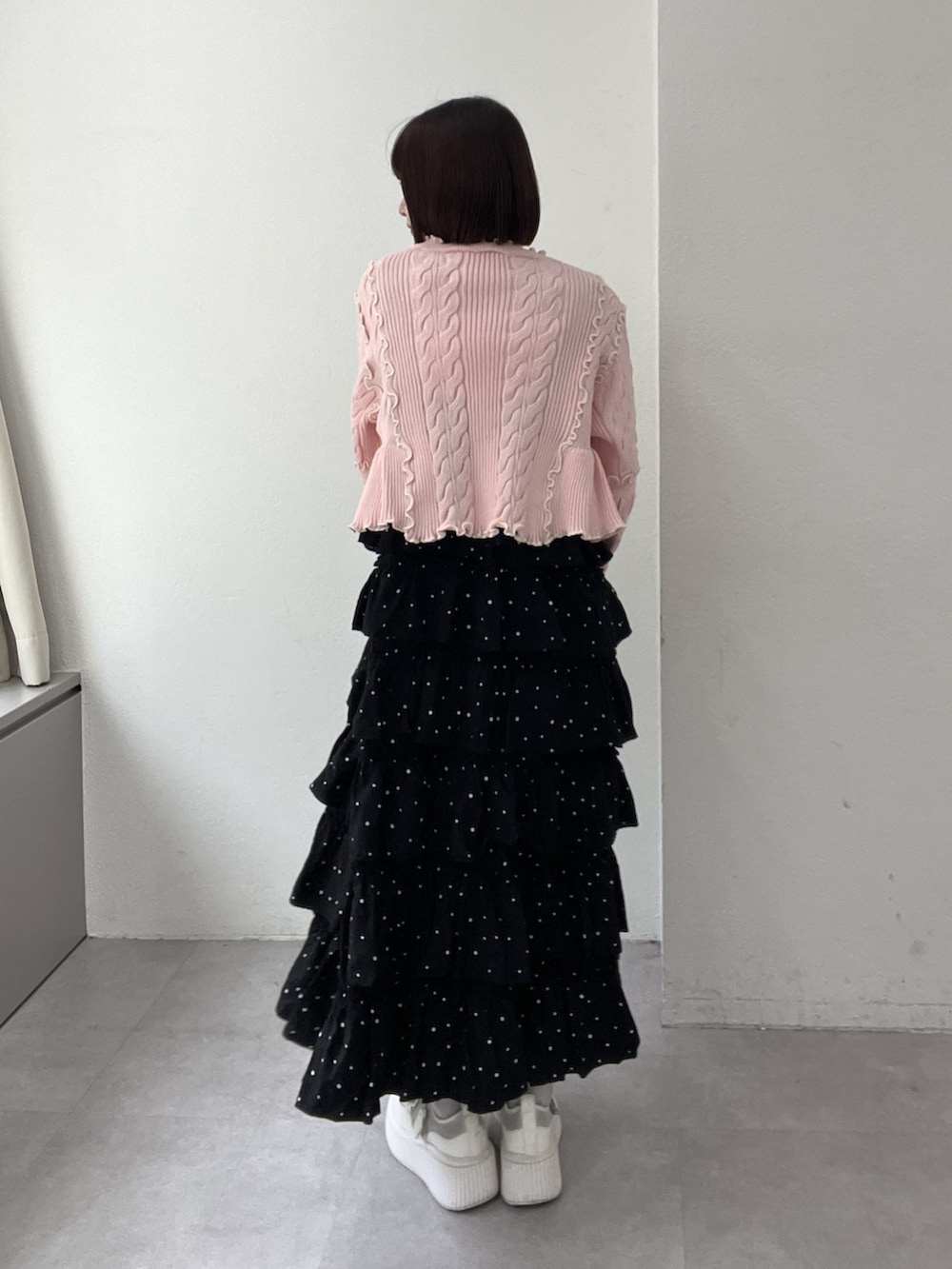 ブラック系のジャンパースカート、ピンク系のカーディガン/ボレロ、ブルー系のボストンバッグを着用したレディースの冬コーディネートの3枚目の写真