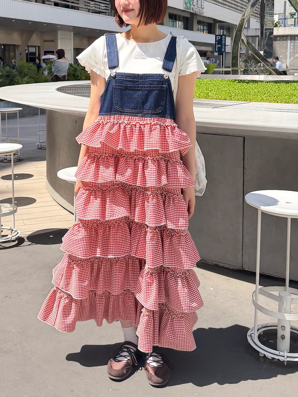 レッド系のジャンパースカートを着用したレディースの春コーディネートの4枚目の写真