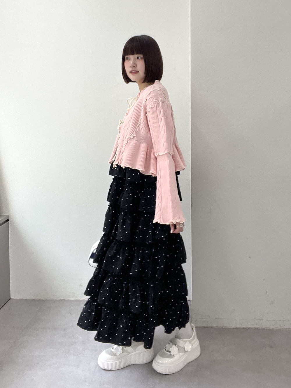 ブラック系のジャンパースカート、ピンク系のカーディガン/ボレロ、ブルー系のボストンバッグを着用したレディースの冬コーディネートの2枚目の写真