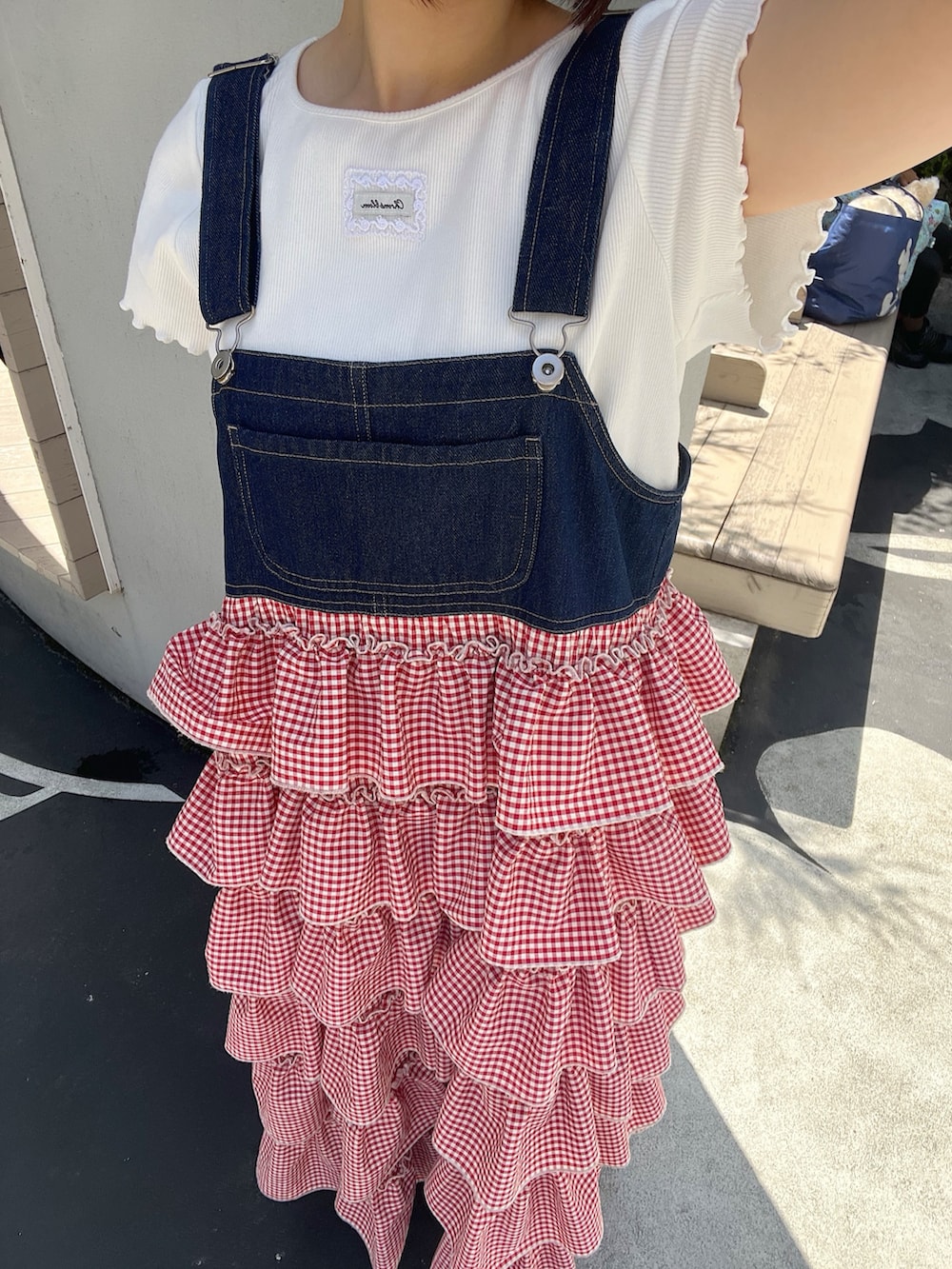 レッド系のジャンパースカートを着用したレディースの春コーディネートの5枚目の写真