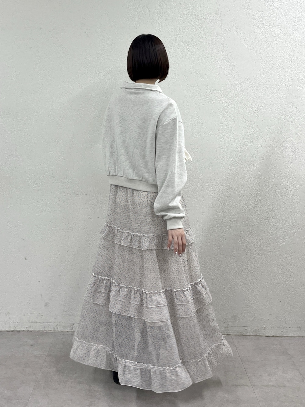 オレンジ系のワンピース、ホワイト系のTシャツ/カットソー、ブラウン系のブーツを着用したレディースの春コーディネートの2枚目の写真