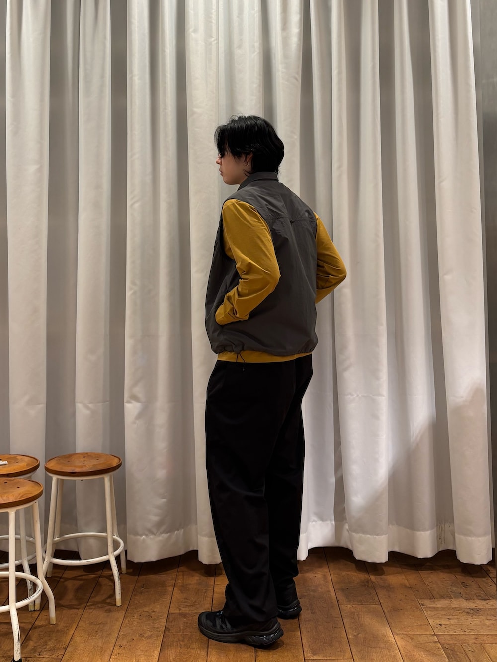 グレー系のベスト、ブラック系のその他パンツを着用したメンズの春コーディネートの2枚目の写真