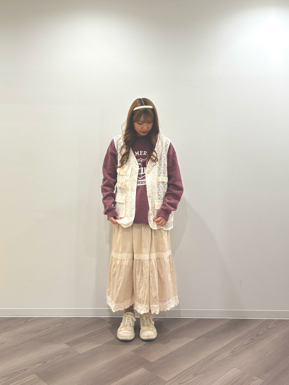 ホワイト系のスニーカー、ベージュ系のスカート、ホワイト系のベストを着用したレディースの冬コーディネートの3枚目の写真