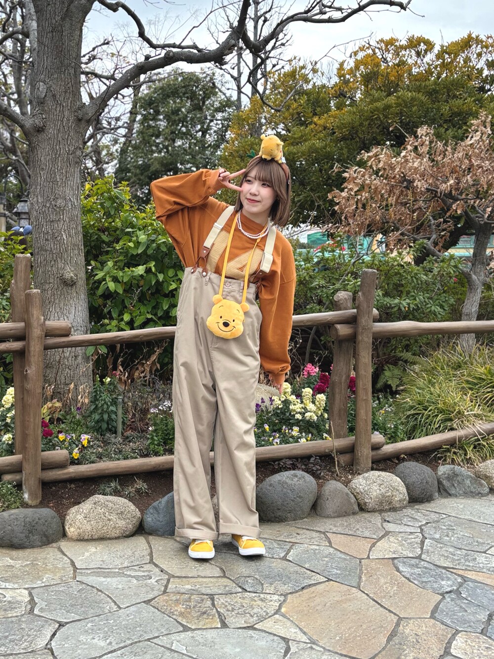 ベージュ系のチノパンツ、オレンジ系のスウェット、ホワイト系のネックレスを着用したレディースの春コーディネートの2枚目の写真