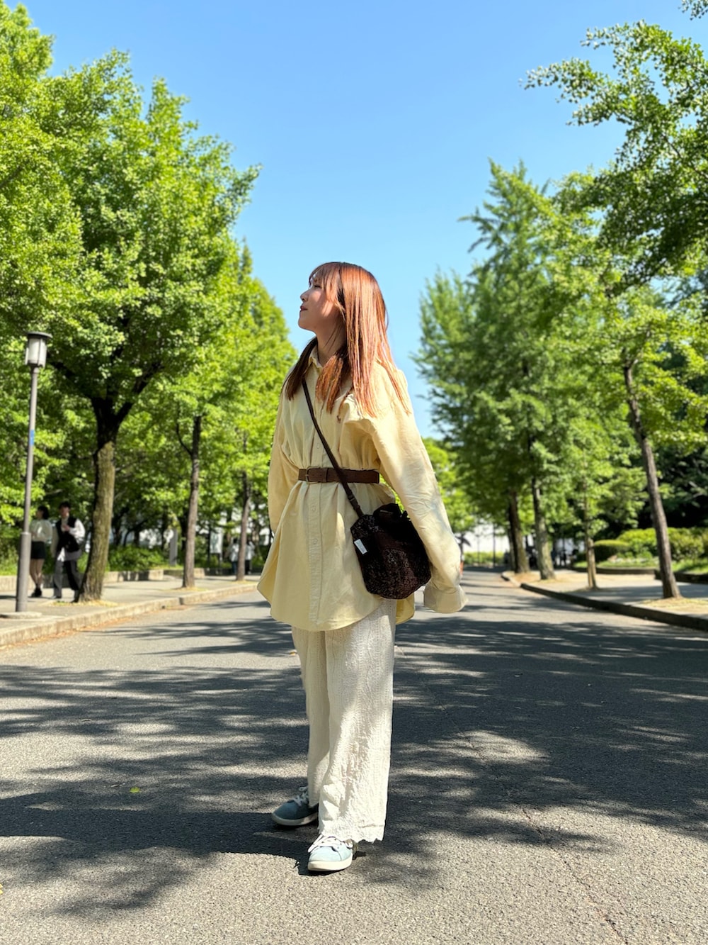 イエロー系のシャツ/ブラウス、ホワイト系のパンツ、ブラウン系のショルダーバッグを着用したレディースの冬コーディネートの2枚目の写真